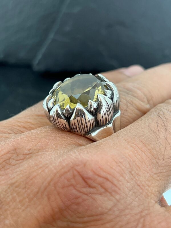 Close-up of a unique silver ring with a gemstone on a finger.