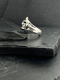 Elegant silver ring with a unique intertwined design on a dark slate surface.