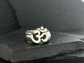 A silver ring featuring the Om symbol on a dark surface.
