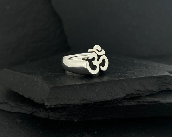 Silver ring featuring a prominent Om symbol on a dark background.