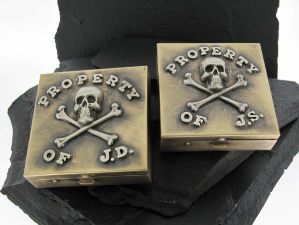 Two metal blocks engraved with 'PROPERTY OF J.D.' and a skull and crossbones.