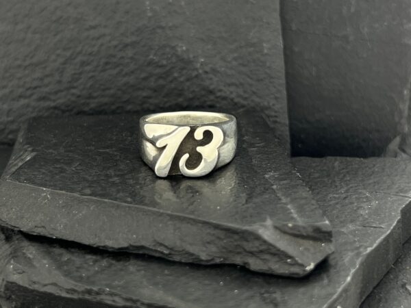Silver ring with the number 73 engraved on it.