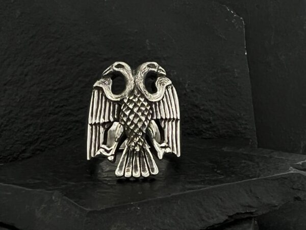 Silver double-headed eagle emblem on black fabric.