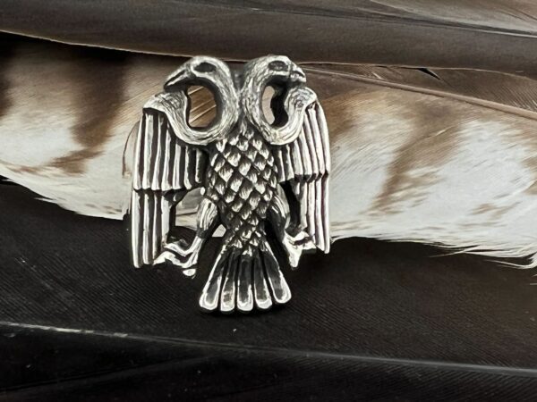 Silver eagle brooch with detailed feathers on a leather surface.