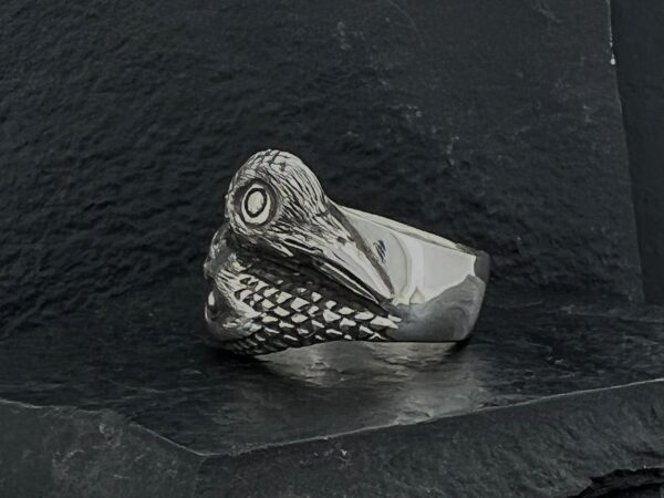 A silver ring shaped like a bird's head with detailed feathers.