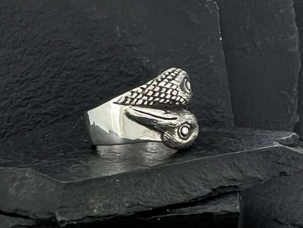 Close-up of a silver ring shaped like a snake coiled with detailed scales.