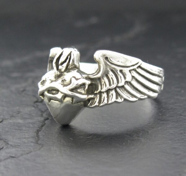 Silver ring shaped like a winged heart with a flame on top.