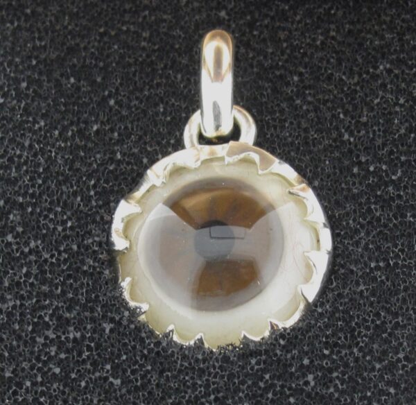 A round glass pendant with a silver frame on a black background.