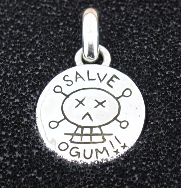 Round silver pendant with 'SALVE OGUM' and a skull design.