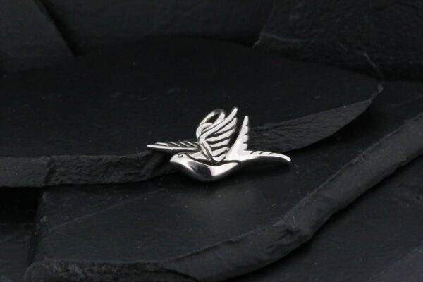 Silver bird brooch on black fabric.