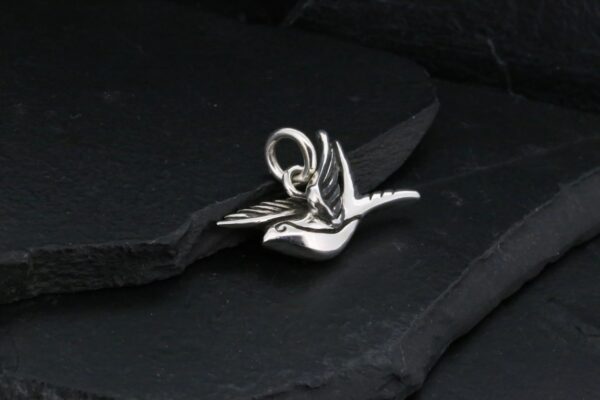 Elegant silver dragonfly pendant on a dark slate surface.
