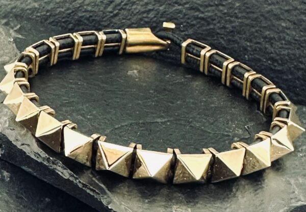 Close-up of a stylish pyramid-studded bracelet on a dark surface.