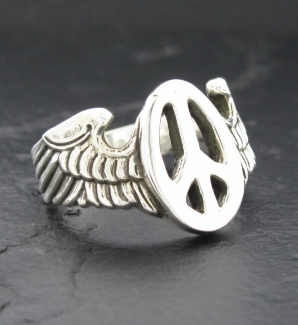 Silver ring with peace symbol and wing design.