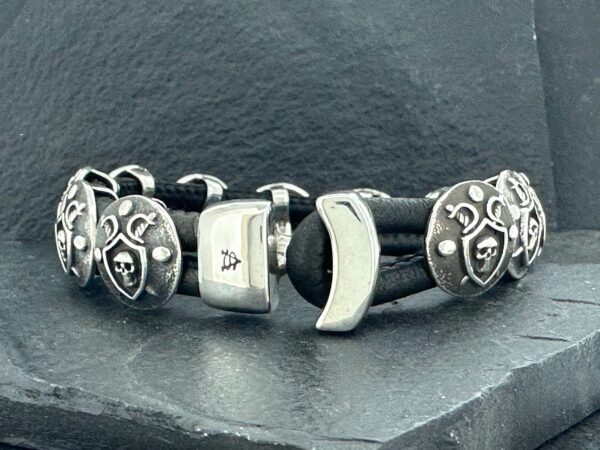 Close-up of a silver and black charm bracelet with theatrical mask charms.