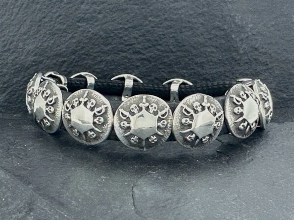Close-up of silver cufflinks with intricate designs on a dark surface.