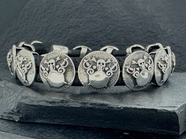 Close-up of four silver rings with intricate owl designs on a dark surface.