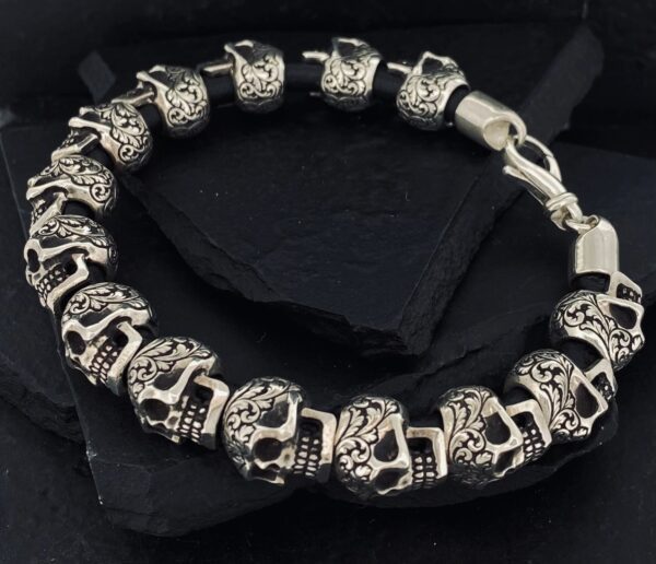 Silver skull-themed bracelet with intricate detailing on a black background.
