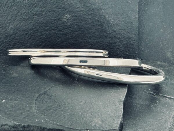 Two silver knives with black handles placed on a dark surface.