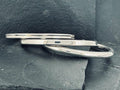 Two silver knives with black handles placed on a dark surface.