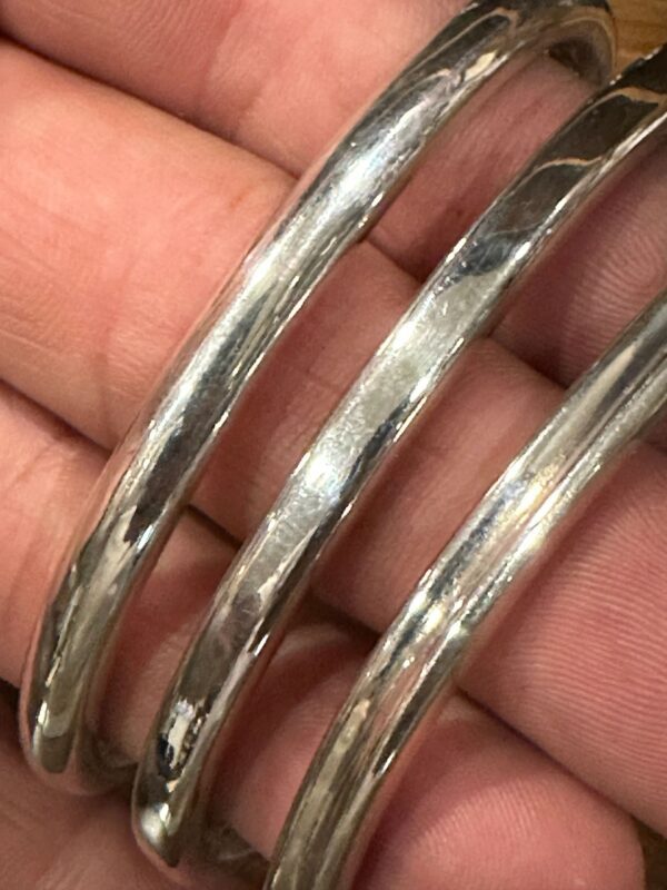 Close-up of shiny metallic bangles held in hand.