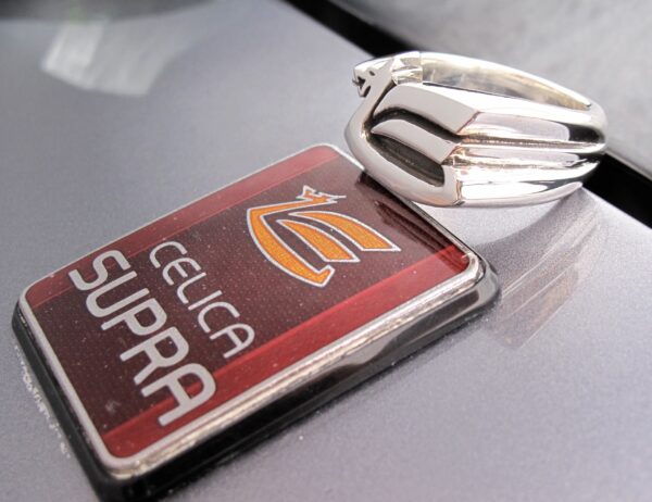 Close-up of a Celica Supra car emblem with a hood ornament.