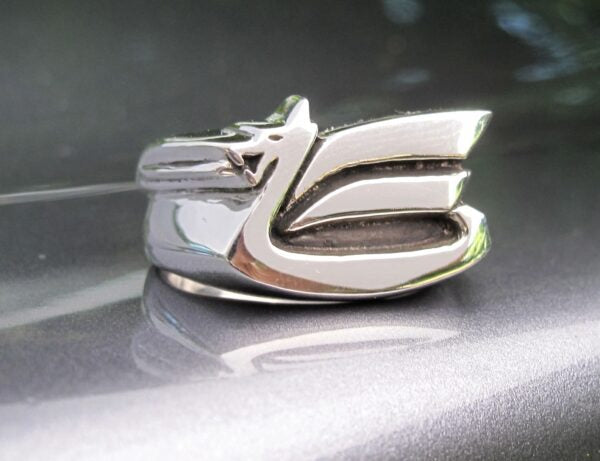 Close-up of a shiny chrome car emblem with stylized lettering.
