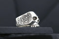 A detailed silver skull ring with intricate floral engravings.