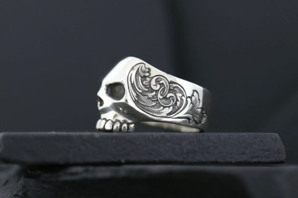 A silver skull ring with ornate side detailing.