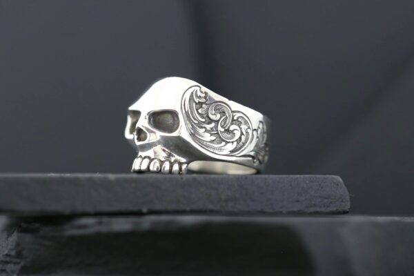 A detailed silver skull ring with intricate side engravings.