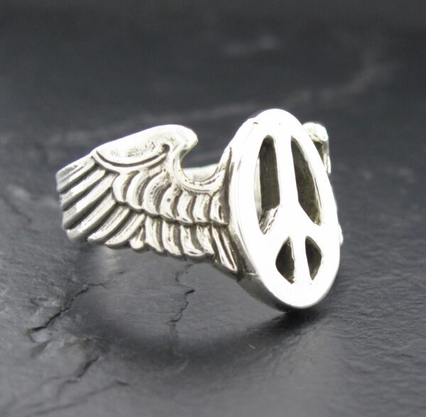 Silver ring with a wing and peace symbol design.