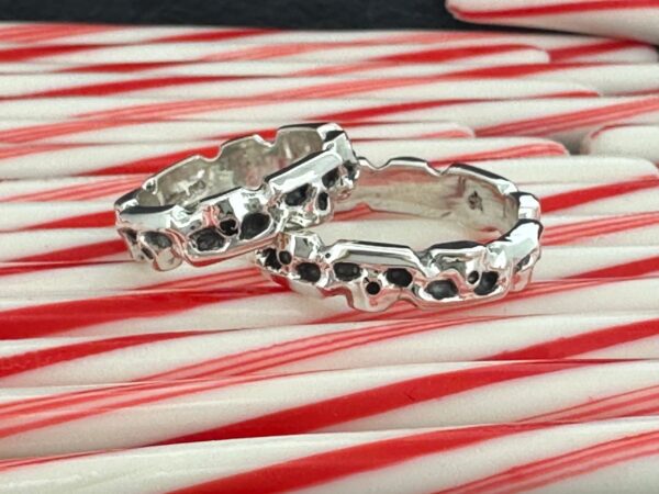Two silver skull-themed rings on red and white striped surface.