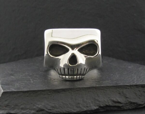 A silver skull-shaped ring with deep eye sockets and teeth detail.