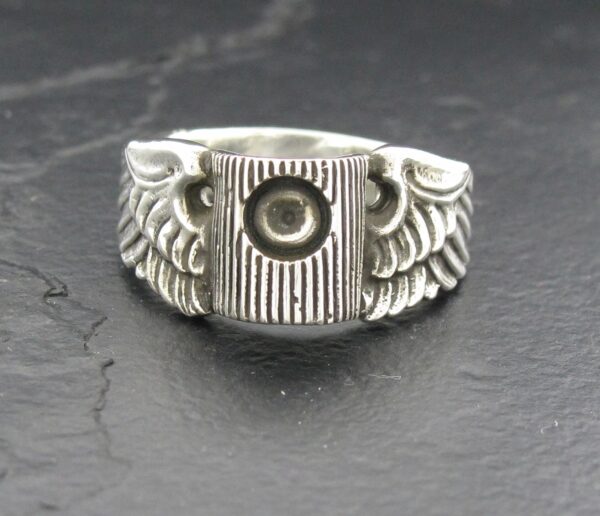 Silver ring with wings and a central circular design.