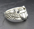 Close-up of a silver ring with detailed wing and grenade design.