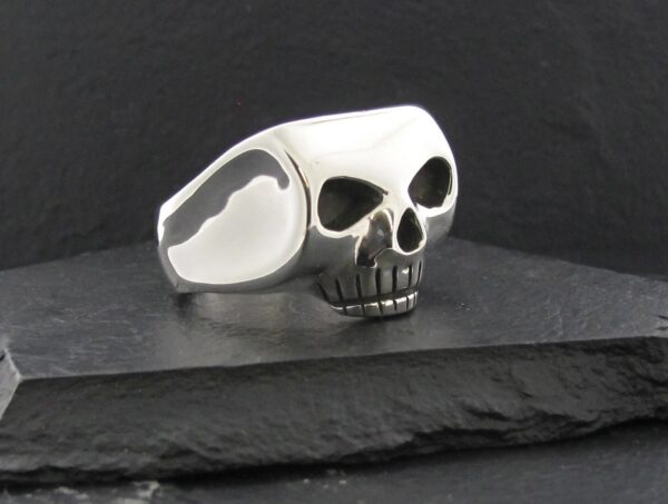 Polished silver skull ring with hollow eyes and detailed teeth.
