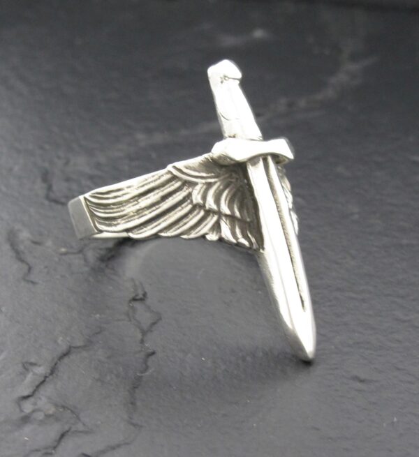 A silver pendant shaped like a sword with a wing attached.