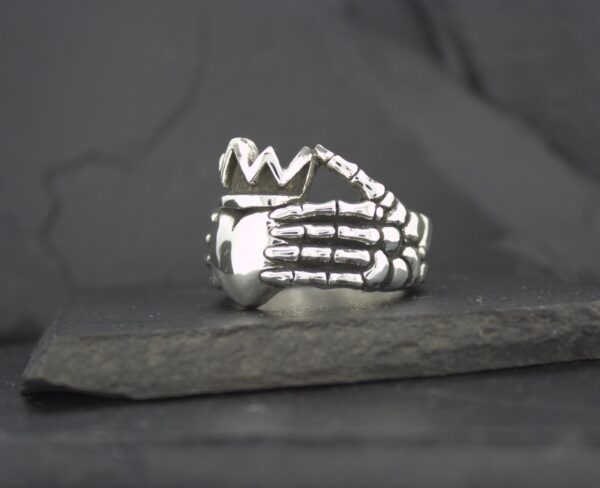 Silver ring shaped like a skeletal hand wrapping around a finger.