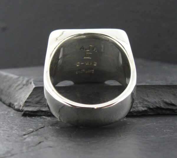 Close-up of the inside of a silver ring with engraved text and numbers.