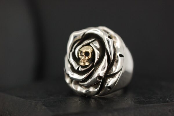 A silver ring shaped like a rose with a skull in the center.