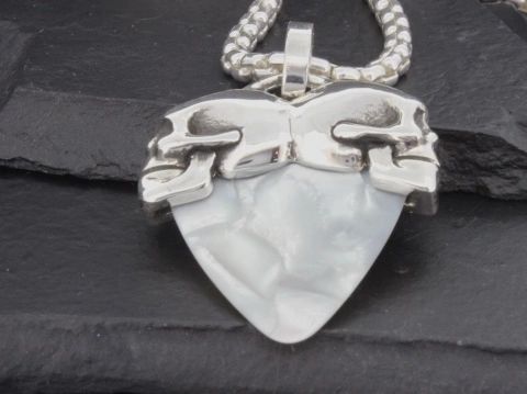 Close-up of a guitar pick pendant with a silver chain.