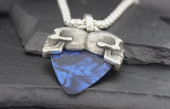 Close-up of a guitar pick pendant with a silver holder on a chain.
