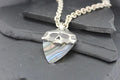Close-up of a silver arrowhead pendant with intricate details on a chain.