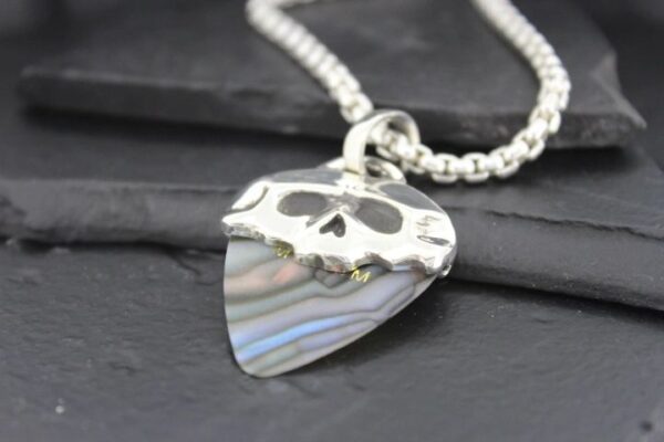 Silver skull pendant on a guitar pick-shaped charm with a chain.