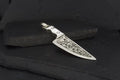 Intricately engraved metal knife with a detailed handle design.
