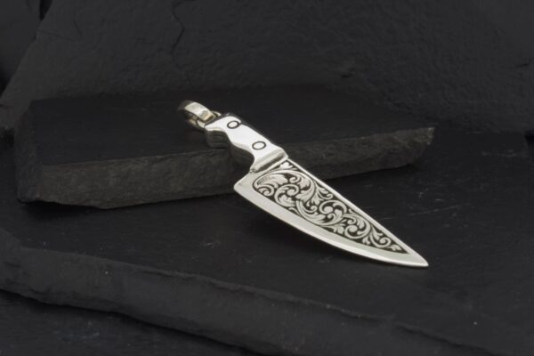 Intricately engraved metal knife with a detailed handle design.