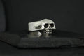 Silver skull-shaped ring on a black surface.