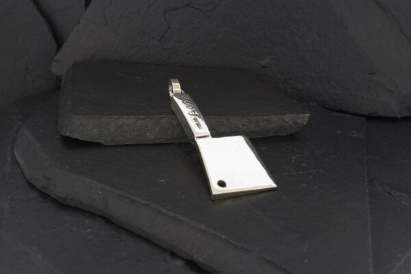 A metallic tool with a flat, angled blade on a dark surface.