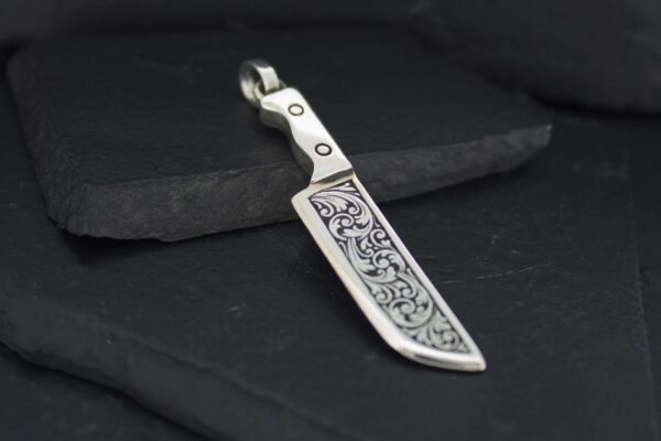 Intricately designed metal pendant resembling a small sword or blade.