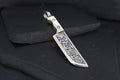 Intricately designed metal pendant resembling a small sword or blade.