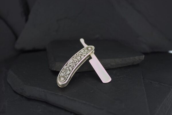 Intricately designed vintage straight razor with a floral pattern on the handle.